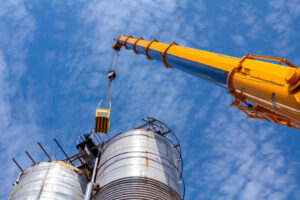 Mobile crane with hook and straps is raising work platform, basket.