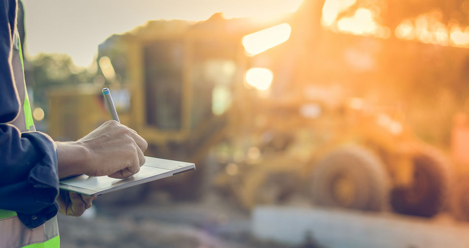 Construction Worker Writing on Clipboard Surveying Worksite