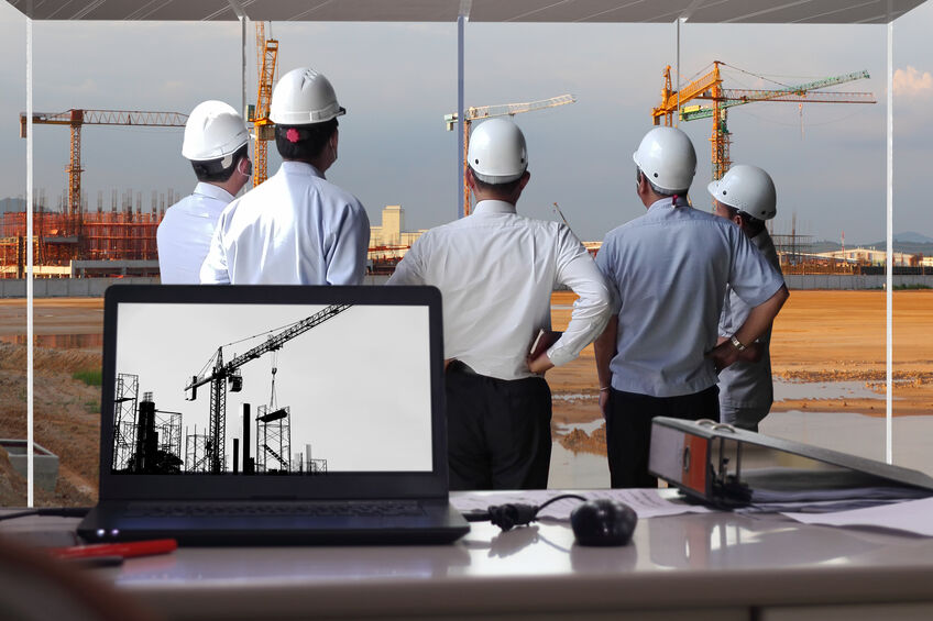 Construction team looking at cranes in the distance, planning how to best safely operate them to prevent accidents.